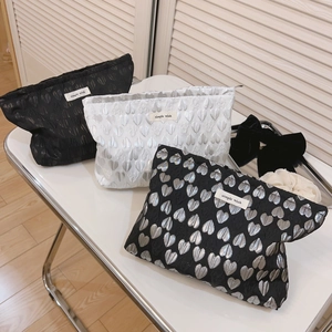 Set of three minimalist jacquard heart makeup bags with simple wish labels on white table
