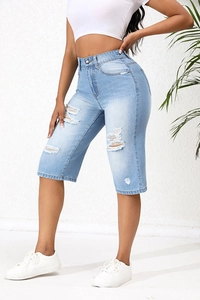 Detail of high waist light blue distressed denim Bermuda shorts with frayed hole accents