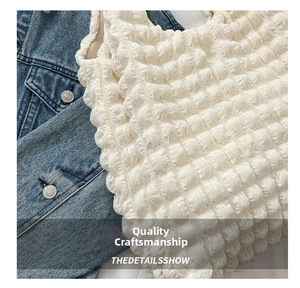 Détail de la texture gaufrée crème sur un sac seau élégant pour femme en tissu