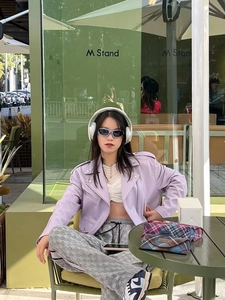 Fashionable model wearing Y2K cat-eye sports sunglasses with a purple biker jacket