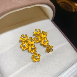 Close-up of golden floral drop earrings with sparkling zircon centers in a jewelry box