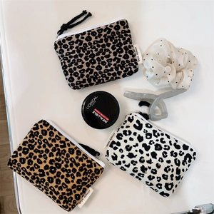 Three leopard print mini zip pouches in brown, yellow, and white on a clean white background