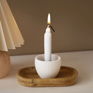 Portacandela minimalista in ceramica a coste su un vassoio in legno naturale