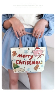 Close-up of white canvas tote with Christmas puppy and gingerbread patterns and snap closure