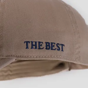 Close-up of high-quality navy blue 'THE BEST' embroidery on khaki cotton baseball cap