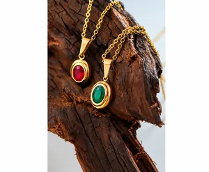Close-up of vintage oval ruby and emerald pendant necklaces on natural wood base