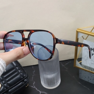 Detail of tortoise shell aviator sunglasses with light blue lenses held by hand