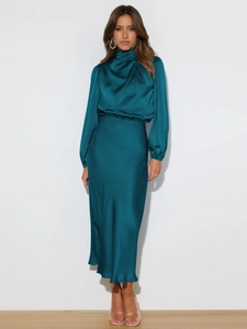 Detailed texture of dark teal satin dress fabric showing high glossy finish and elegant drape