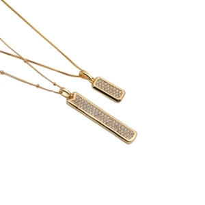 Ensemble de deux pendentifs rectangulaires dorés avec cristaux de zircon sur fond blanc
