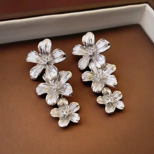 Detail of silver flower earrings with brushed metal texture and vertical floral petals