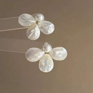 Detailed close-up of petal earrings with shell texture and white pearl center