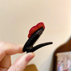 Dettaglio di un fermaglio per capelli vintage con cuore di velluto rosso e base antiscivolo