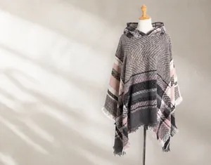 Detailopname van roze en grijze geruite gebreide poncho met franjes op een etalagepop
