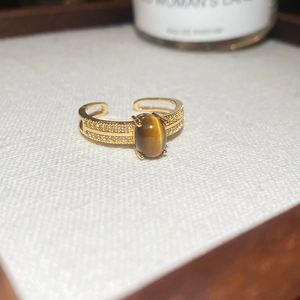Macro shot of gold plated tiger eye ring with shimmering zircon accents on white card