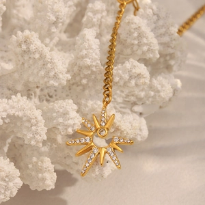 Macro shot of 18K gold plated North Star pendant with crystals on white coral texture