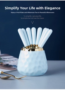 Detail of light blue ceramic jar with gold stainless steel fruit forks and spoons set