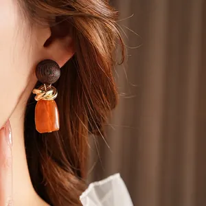 Vintage wood and amber resin geometric earrings with gold metal rings on a model