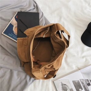 Brown canvas crossbody bag with top zipper and spacious interior in a lifestyle flat lay view