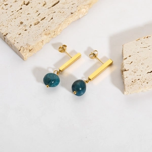 Detail view of gold rectangular drop earrings with blue natural stone beads on stone