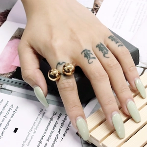 Nahaufnahme eines goldenen Doppelball-Rings am Finger des Models mit Spiegelglanz