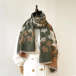 Close-up of thick green scarf with brown ginkgo leaf pattern and tassel detail