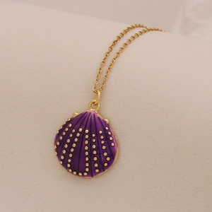 Macro detail of purple conch seashell pendant with gold dots on stainless steel chain