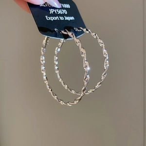 Close-up of silver S925 large hoop earrings featuring a stylish twisted metal design