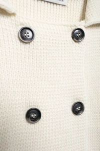 Détail de l'encolure du cardigan blanc en maille avec boutons gris à double boutonnage