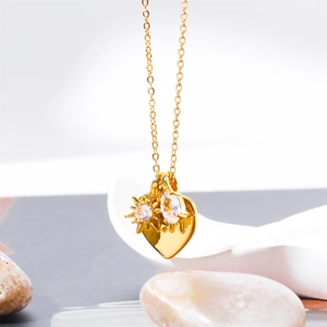 Close-up of golden heart pendant with star engraving and sparkling zircons on fine chain
