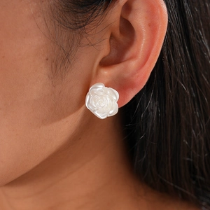 Close-up of white resin rose flower stud earring with pearl luster worn on an ear
