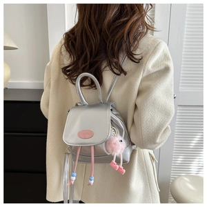 Dettaglio mini zaino in pelle PU argento con cordoncini rosa e ciondolo mostro di peluche