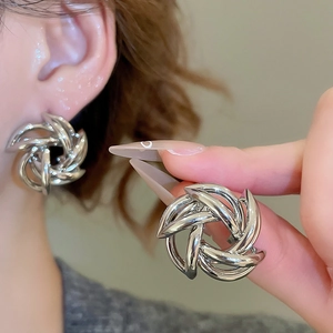 Macro detail of silver metal hollow woven knot earring with polished mirror surface