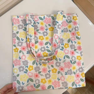 Detail of floral printed canvas tote bag with pink and yellow flowers on white fabric