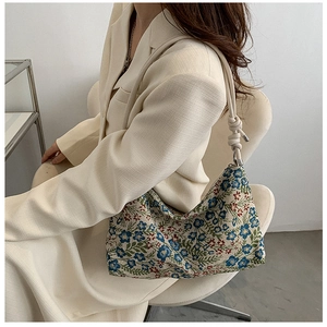 Detail showing blue and red floral jacquard fabric and knotted rope strap on underarm bag