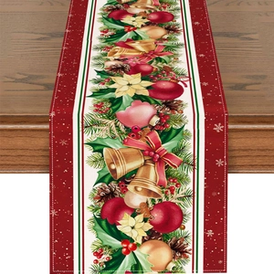 Detail of Christmas table runner with bells, poinsettias and pine needles on wood table