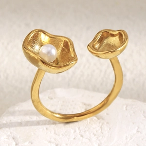 Detail of 18K gold-plated open ring featuring a white pearl on a textured metal shell