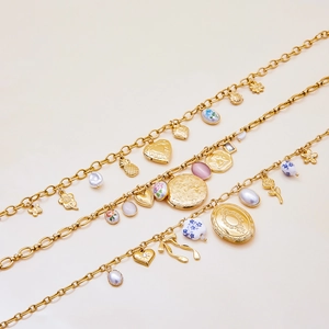 Gros plan détaillé de bracelets plaqués or 18 carats avec breloques cœur, fleur et perle