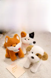 Close-up of plush stuffed fox, cat, and dog toys with lace scarves on soft carpet