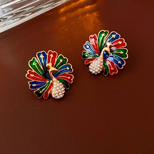 Macro detail of vintage peacock earrings with colorful enamel and inlaid pearls