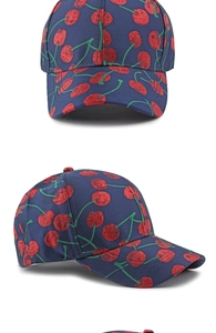 Detailed close-up of navy blue baseball cap with red cherry embroidery and fabric texture