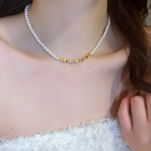 Detail of white pearls and geometric gold metal beads on a chic layered choker necklace