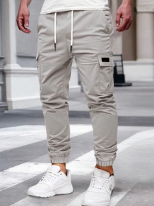 Detail of light grey cargo pants showing large side pockets and cotton twill texture