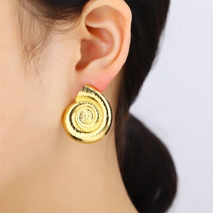 Macro shot of gold spiral textured earrings with sleek snail shell shape on model
