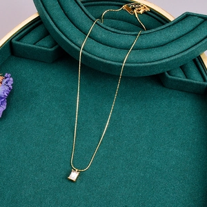 Macro detail of rectangle zircon pendant on gold chain over green velvet display