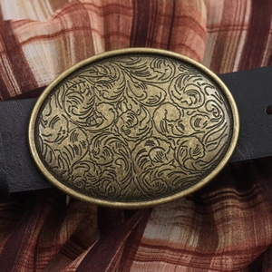 Close-up of vintage bronze belt buckle with intricate floral carvings on a plaid dress