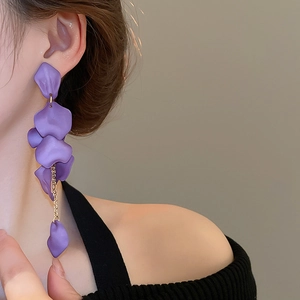 Detail view of purple petal tassel earrings with gold chain on model neck