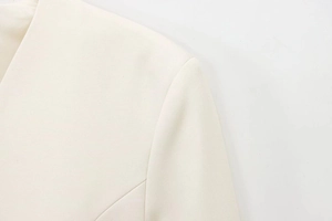 Dettaglio della cucitura della spalla e del tessuto a trama fine del blazer color avorio