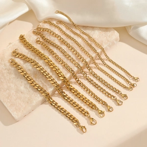Golden stainless steel curb chains in various sizes displayed on a luxury stone tray
