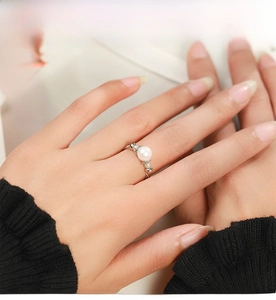 Detail shot of a white round pearl and micro-beaded silver band on a model hand