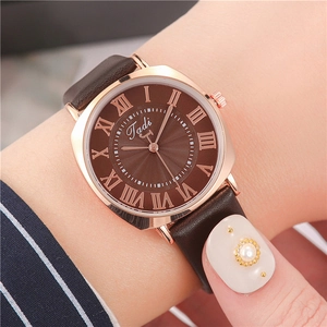 Gros plan d'une montre femme à quartz avec cadran brun soleil et chiffres romains sur cuir